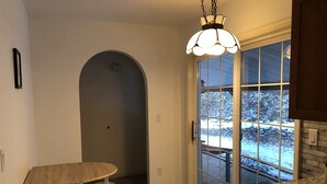 Ett kök med en bänkskiva i granit, ett matbord i trä med tillhörande stolar, ett stort fönster med utsikt över ett snötäckt landskap och en hängande lampa.