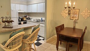 A kitchen with white cabinets, a dining area with a wooden table and chairs, and a chandelier. - A3 Pet friendly, 1 BR, 1 BA, with tile floors Ask about long term rates (St. Simons Island)