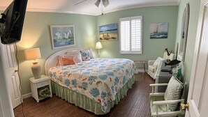 A bedroom with a bed, a desk, a chair, a lamp, and artwork on the walls. - A3 Pet friendly, 1 BR, 1 BA, with tile floors Ask about long term rates (St. Simons Island)