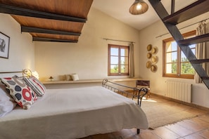 Un dormitorio con cama, ventana, radiador y escalera.