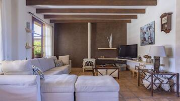 Una sala de estar con sofá, televisión, mesa y chimenea.