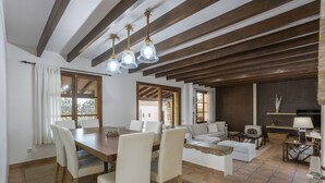 A spacious living area with a wooden dining table, white chairs, a sofa, and a fireplace. - Fantastic villa with 4 bedrooms, 3 bathrooms, wifi, barbecue, terraces and pool (Binissalem)