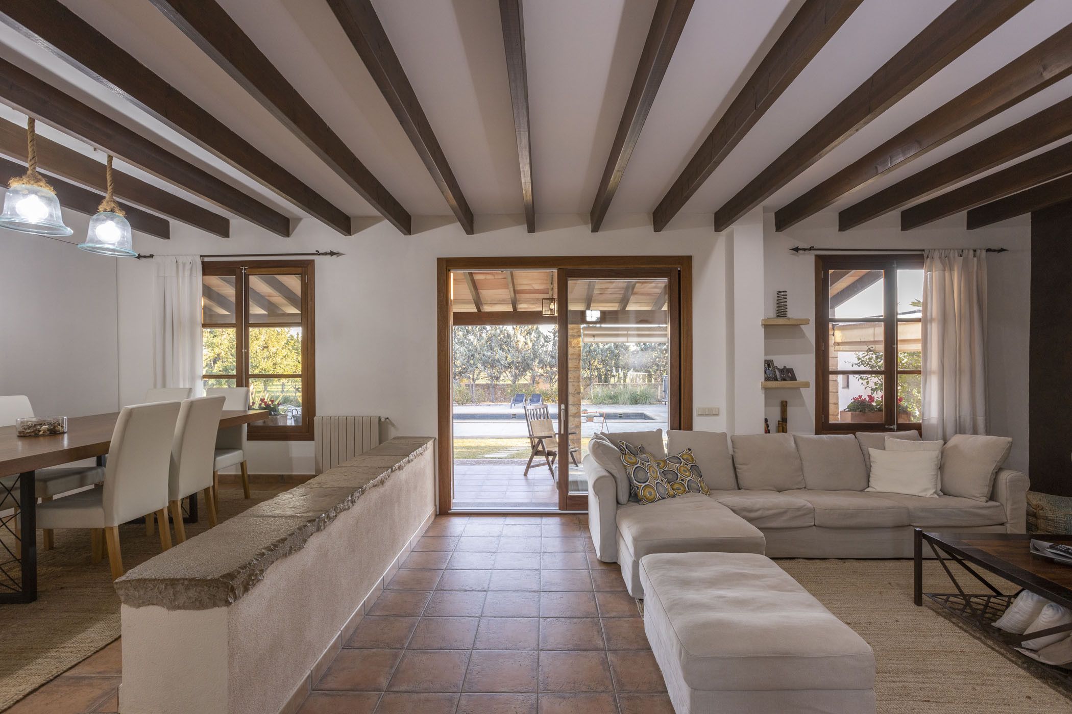 Amplia sala de estar con un sofá grande, una mesa de comedor con sillas y una cocina visible a través de una puerta abierta.