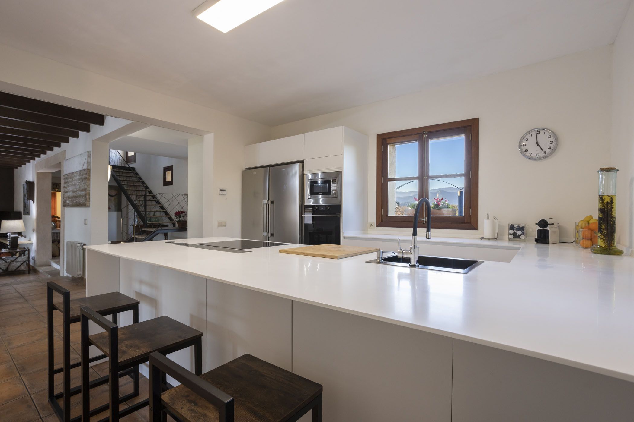 A modern kitchen with a large island, stainless steel appliances, and a view of the outdoors.