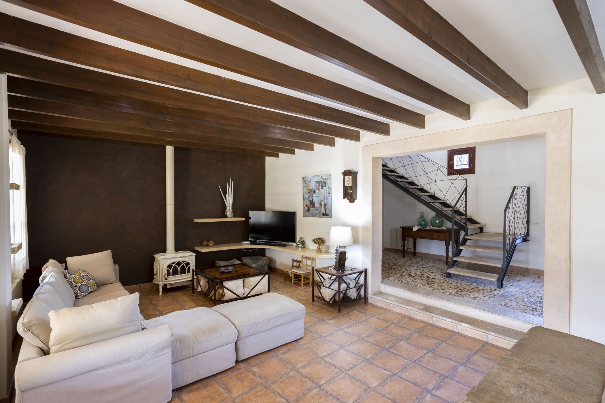 Una sala de estar con sofá, televisión y chimenea. Una escalera conduce a otro nivel.