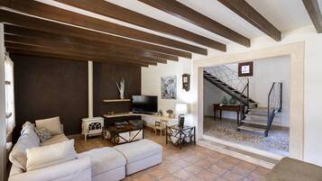 Una sala de estar con sofá, televisión y chimenea. Una escalera conduce a otro nivel.