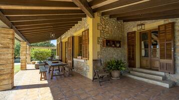 Un patio cubierto con paredes de piedra, contraventanas de madera y un banco de piedra.