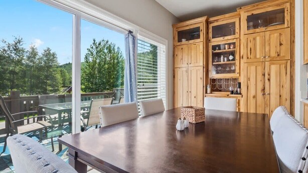 A dining area with a large table, chairs, and wooden cabinets with glass doors. - The Eagle's Nest   — 4BR All-En-Suite Townhome near Beaver Creek & Vail, Sleeps 9 (Vail)