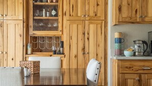 A wooden kitchen with cabinets, a dining table, and a chair. - The Eagle's Nest — 4BR All-En-Suite Townhome near Beaver Creek & Vail, Sleeps 9 (Vail)