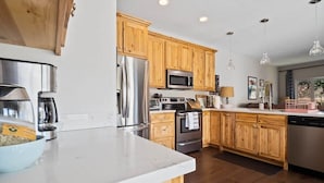 A modern kitchen with wooden cabinets, stainless steel appliances, and a marble countertop. - The Eagle's Nest — 4BR All-En-Suite Townhome near Beaver Creek & Vail, Sleeps 9 (Vail)