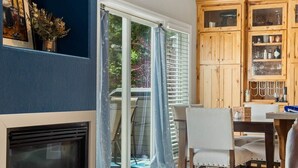 A room with a fireplace, a dining area with chairs, a table, and a kitchen area with cabinets. - The Eagle's Nest — 4BR All-En-Suite Townhome near Beaver Creek & Vail, Sleeps 9 (Vail)