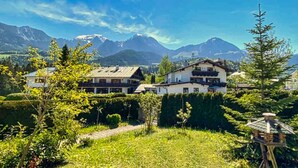 A mountain-view property with multiple buildings, a well-maintained garden, and a clear sky.