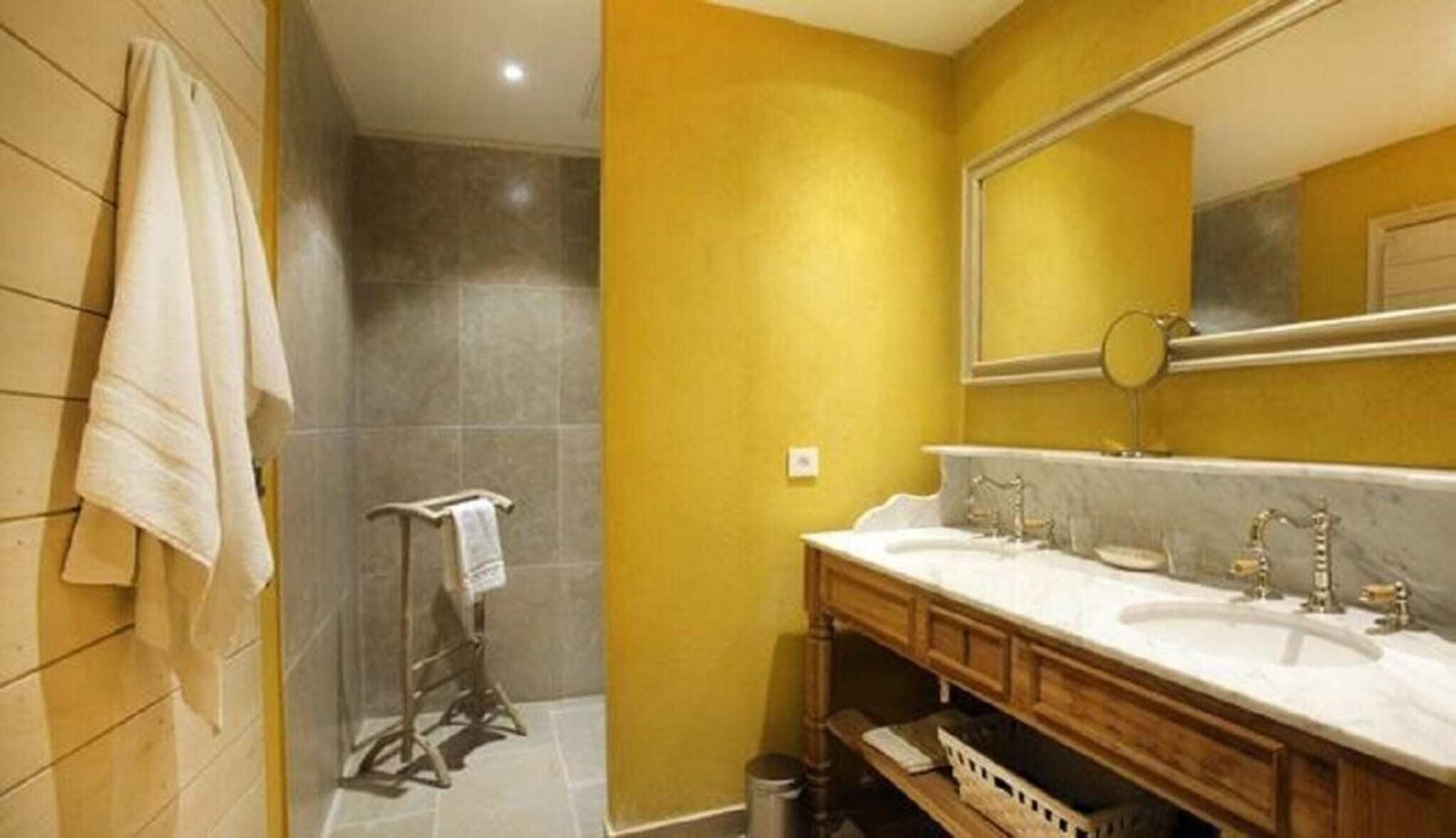 Une salle de bain avec deux lavabos, un miroir et un porte-serviettes.