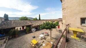 A courtyard with outdoor seating, a pergola, and a view of the surrounding landscape.