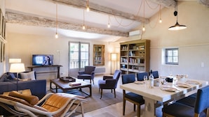 A spacious living area with a dining table set for a meal, a television, and a bookshelf. - Sauvignon (Robion)