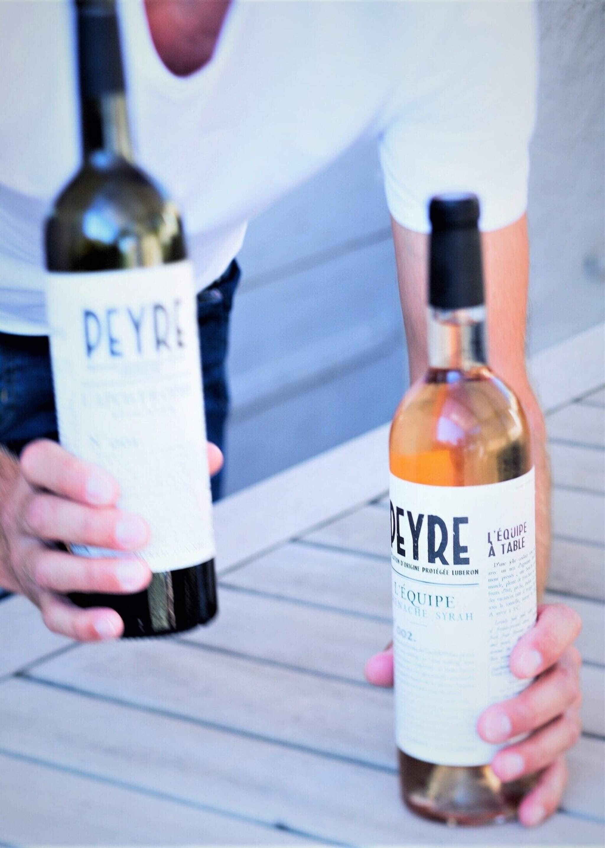 Två flaskor Peyre-vin som hålls i en persons hand.
