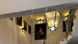 A staircase with white steps and a metal railing, leading to a landing area with a chair and several colorful vases. - Sauvignon (Robion)