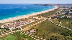 Luftaufnahme einer Küstenlandschaft mit Strand, Wohnhäusern und einem Golfplatz.