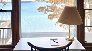 Een kamer met uitzicht op een meer, een tafel met een lamp en een stoel.