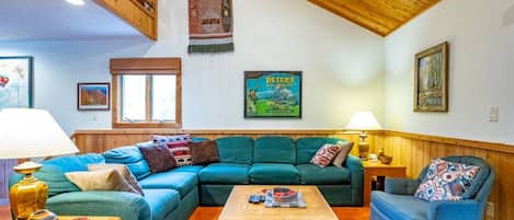 Una sala de estar acogedora con un sofá modular, una mesa de centro y un sillón estampado.