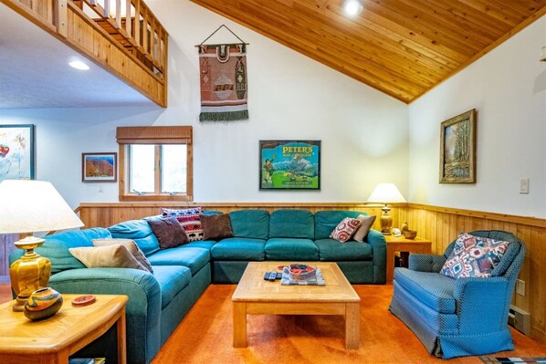 A cozy living room with a sectional sofa, a coffee table, and a patterned armchair.