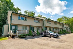 A two-story motel with a gravel driveway and a parked SUV.