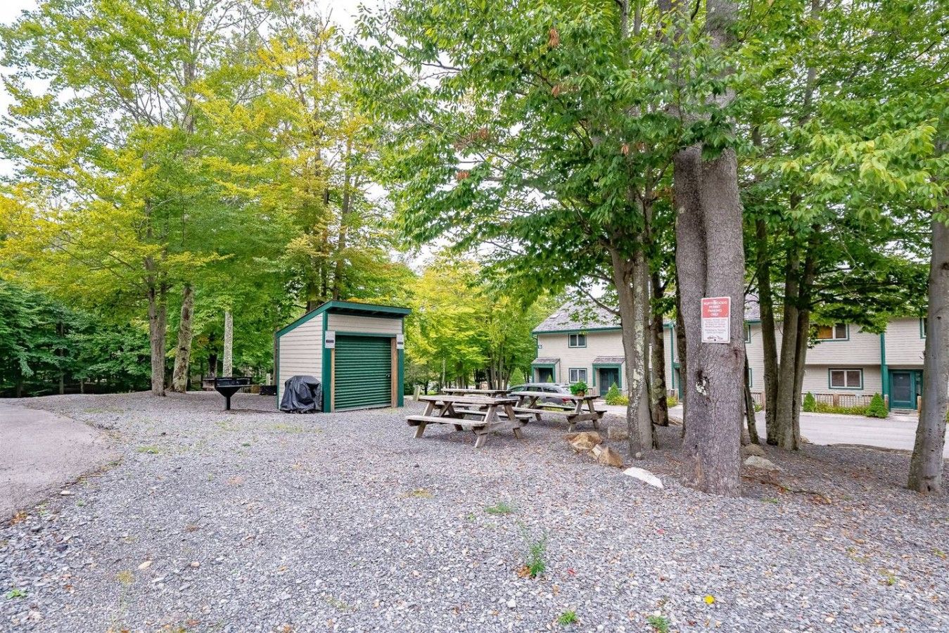Ein Campingplatz mit Picknicktischen, einem Schuppen und einem Gebäude mit einer grünen Tür.