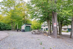 Um camping com mesas de piquenique, um galpão e um edifício com porta verde.