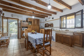 A kitchen with wooden cabinets, a dining table with chairs, and a window with decorative iron bars.