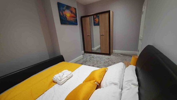 A hotel room with a bed, a wardrobe, and a painting on the wall. - Breeze on Southend in Essex (Southend-on-Sea)