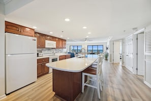 Une cuisine moderne avec des meubles en bois, un îlot central et une vue sur l’extérieur.