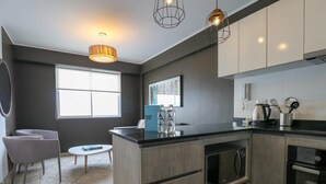 Een moderne keuken met donkere kastjes, een centraal eiland en roestvrijstalen apparatuur.