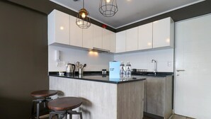 Een moderne keuken met witte kastjes, een zwart aanrecht en twee krukken.