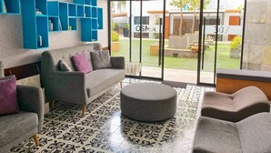 A modern living room with a grey sofa, ottoman, and blue shelving unit.