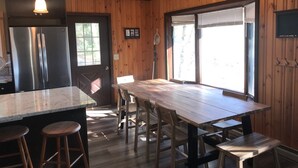 A modern kitchen with a large island, wooden panel walls, and a stainless steel refrigerator. - Great for Families & Groups! (Windham,)