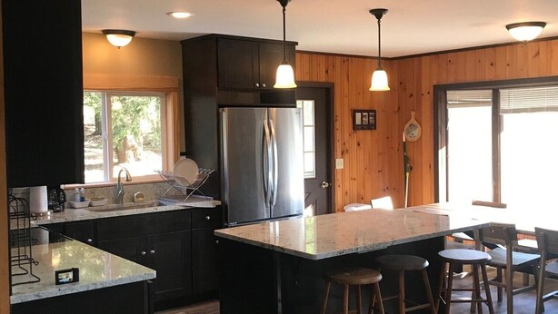 A modern kitchen with a central island, bar stools, and a dining area with a sofa. - Great for Families & Groups! (Windham,)