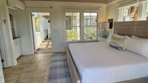 Un dormitorio con techo de madera, una cama, una mesita de noche y un ventanal.
