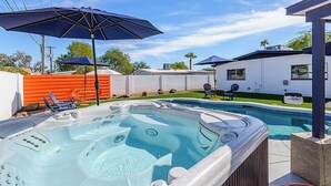 Un jardin avec un jacuzzi, une piscine et un espace salon extérieur.