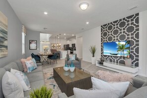 Een moderne woonkamer met een bank, salontafel en een flatscreen televisie bevestigd aan een muur met een geometrisch patroon.