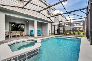 En swimmingpool med et boblebad, udendørs møbler og en overdækket terrasse.