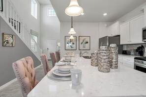 Een moderne keuken met witte kastjes, een marmeren eiland en hanglampen.