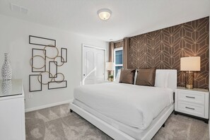 Een slaapkamer met een bed, nachtkastjes, een wanddecoratie met abstracte kunst, een behang met patroon, en een raam met gordijnen.