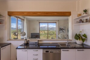 A modern kitchen with a dishwasher, sink, and a window overlooking a mountainous landscape. - Modern villa with 3 bedrooms, 2 bathrooms, wifi, terraces and pool (Inca)