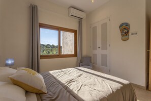 A bedroom with a bed, a window, an air conditioning unit, a door, and a wall decoration. - Modern villa with 3 bedrooms, 2 bathrooms, wifi, terraces and pool (Inca)