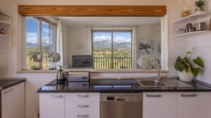 Cuina moderna amb rentaplats, vàter i finestra amb vista a un paisatge de muntanya.