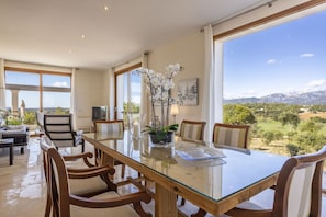 A spacious dining area with a glass table and wooden chairs, large windows offering a view of a mountainous landscape. - Modern villa with 3 bedrooms, 2 bathrooms, wifi, terraces and pool (Inca)