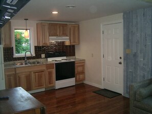 Una cocina compacta con armarios de madera, una estufa y un lavamanos.