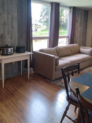 Una sala de estar con un sofá, una mesa de comedor y una ventana con cortinas.