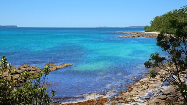 A coastal landscape with clear blue waters, rocky shorelines, and dense greenery. - Husky Sands - Pet Friendly - 5 Mins Walk to Beach (Huskisson)