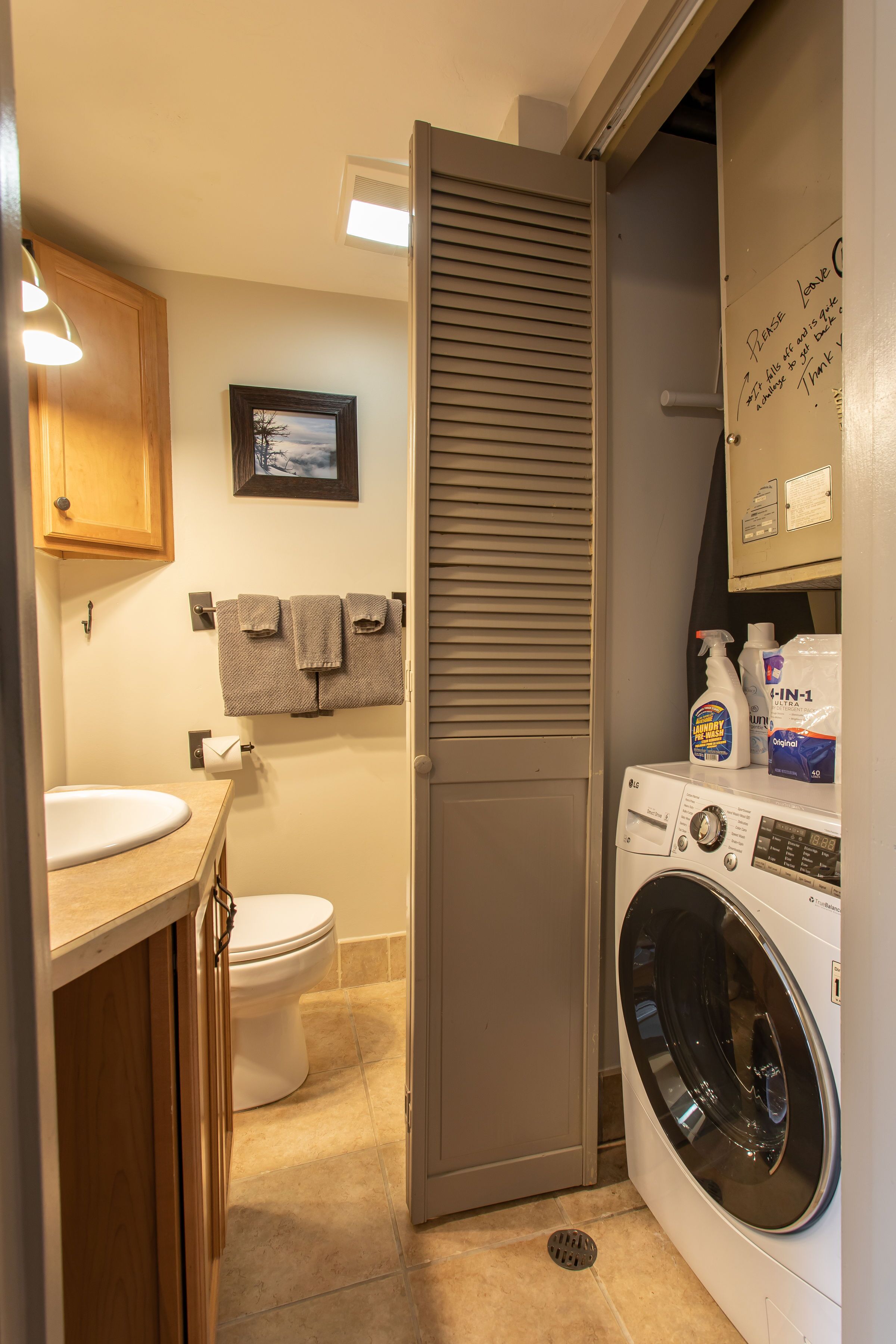 A compact laundry room with a washing machine, a toilet, and a sink.